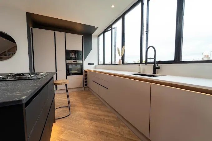 Contemporary kitchen with long window, pale cabinetry and dark island
